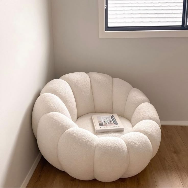Round, cushioned chair in a room with a window and wooden floor.